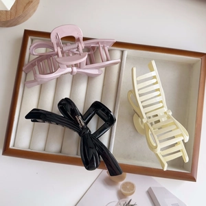 Close-up of elegant ribbon bow hair claws in pink, black, and cream resin colors