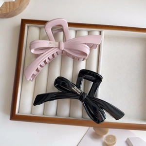 Detail of elegant resin bow hair claws in pink and black with stylish gold lettering