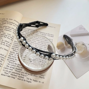 Détail du serre-tête pliable avec double rangée de perles et monture noire sur livres
