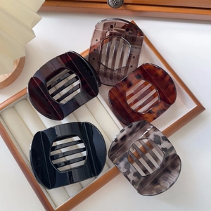 Close-up of five assorted tortoiseshell hair claws in a wooden organizer box