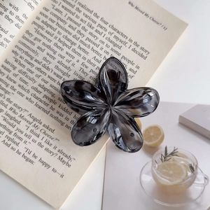 Dettaglio macro di un grande fermaglio per capelli a fiore grigio su un libro aperto