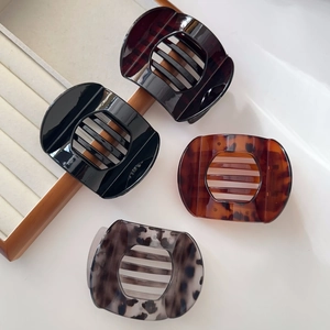 Detail of four retro tortoiseshell hair claw clips in black, amber, and leopard patterns