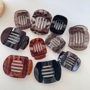 Flat lay detail of large leopard and tortoise shell hair clips on a white surface