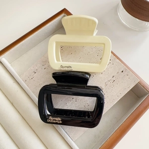 Vue détaillée des pinces à cheveux rectangulaires en noir brillant et blanc crème