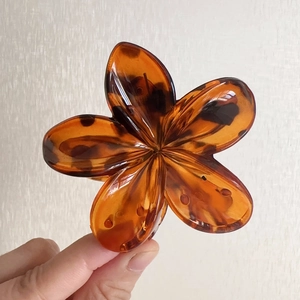 Dettaglio macro della molletta per capelli a fiore in ambra e guscio di tartaruga