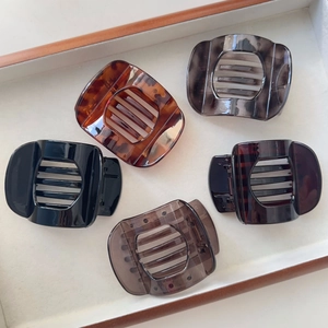 Close-up of five large tortoiseshell hair claws in various colors on a wooden tray