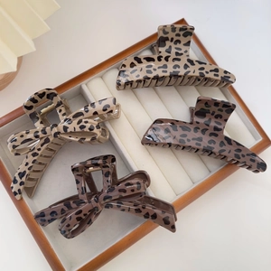 Detailed view of four leopard print hair claws in brown tones with bow and arc shapes