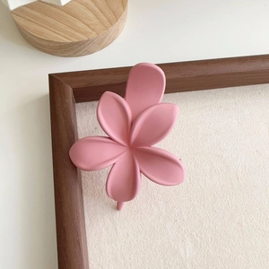 Détail de la pince à cheveux plumeria rose au fini mat sur un cadre en bois