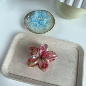 Pince à cheveux fleur avec texture marbrée rose et vert sur un plateau de présentation