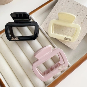 Vue détaillée de pinces à cheveux carrées en noir beige et rose avec texte doré