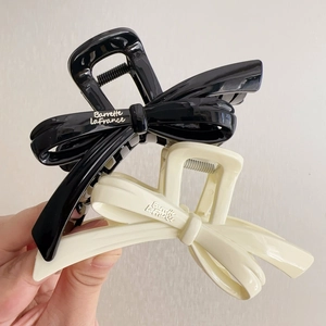 Close-up of glossy bow-shaped hair claws in black and cream with metal spring detail