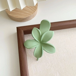 Détail d'une pince à cheveux fleur vert sauge mat sur un fond de cadre vintage