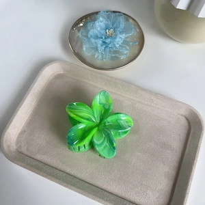 Détail macro d'une pince à cheveux fleur avec texture marbrée verte et bleue