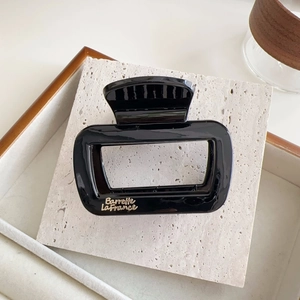 Détail de la pince à cheveux rectangulaire noire avec texte doré Barrette La France