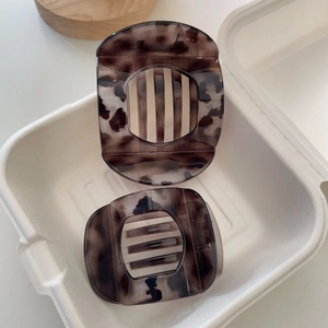 Detail of two tortoise shell hair claws in large and medium sizes on white paper box
