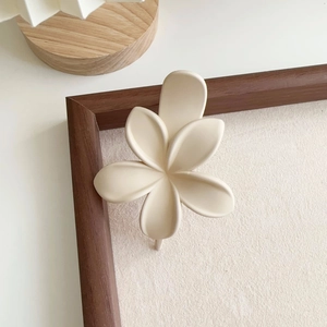 Détail de la pince à cheveux fleur crème avec texture mate sur décor en bois