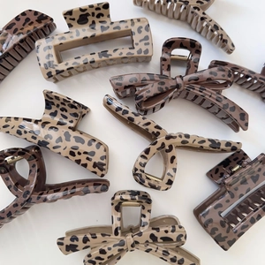 Flat lay of diverse leopard print hair claws in brown and beige with golden metal springs