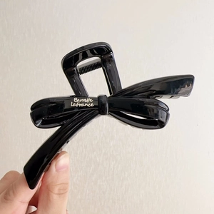 Detail of glossy black resin bow hair claw clip with silver Barrette LaFrance lettering