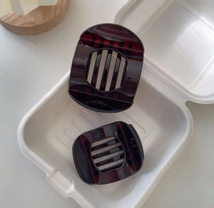 Close-up of tortoiseshell hair clips in different sizes inside a white pulp packaging box