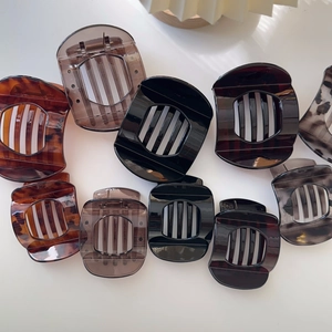 Detailed view of various tortoiseshell and solid color non-slip claw hair clips for styling