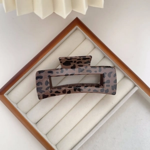 Detailed top view of retro leopard print hair claw clip in a white velvet jewelry tray
