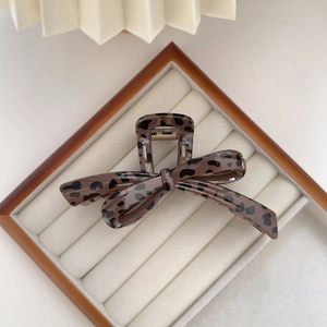 Detail of leopard print bow hair claw clip in a luxury velvet jewelry display box