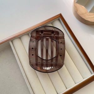 Detailed top view of large brown tortoiseshell hair claw clip on white velvet display tray