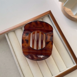 Detail view of tortoiseshell hair claw clip with grid pattern on jewelry tray