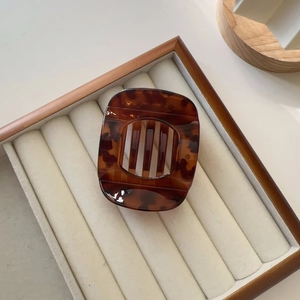 Detail of tortoise shell claw clip with anti-slip teeth on a white velvet tray