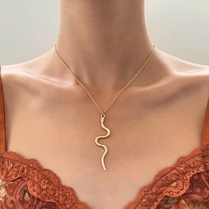 Detailed close-up of a stylish gold snake pendant necklace worn on a female model