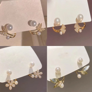 Detail of four gold-tone earrings with pearls and crystals in floral and wing shapes