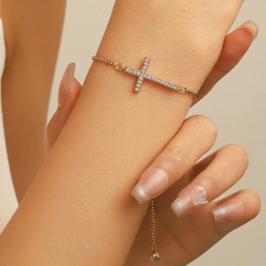 Detailed close-up of a rose gold adjustable bracelet featuring a pavé cross with white zircons
