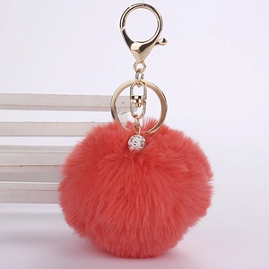 Close-up of pink faux rabbit fur keychain with crystal ball and gold lobster clasp