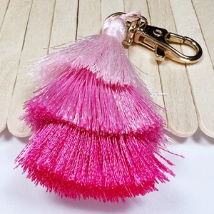 Detail of pink gradient cotton tassel keychain with three-tier fiber layers and gold clasp