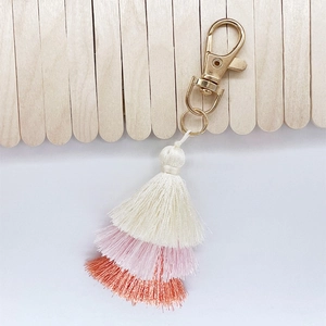 Detailed view of triple-layered tassel keychain in white, pink and coral orange hues