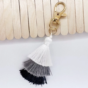 Detailed macro view of a three-tier gradient cotton tassel pendant with gold lobster clasp