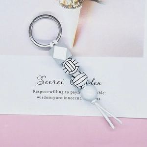 Detail of volleyball beaded keychain featuring silicone beads and white leather tassel