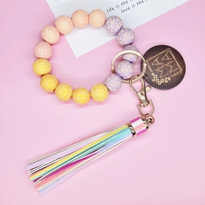 Dettaglio del bracciale con perline leopardate, ciondolo MAMA in legno e nappa colorata