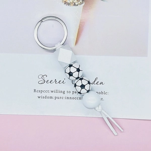 Detail of soccer themed beaded keychain with silicone beads and white tassel accent