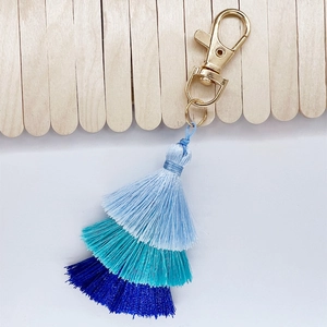 Macro view of blue gradient cotton tassel pendant with golden metal lobster clasp