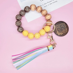 Dettaglio del bracciale di perline leopardate con ciondolo in legno MAMA e nappa colorata