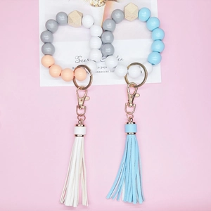 Beaded tassel keychain with wood and silicone beads plus golden ring on pink background