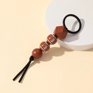 Detail of rugby themed keychain with brown faceted wooden beads and a black tassel charm