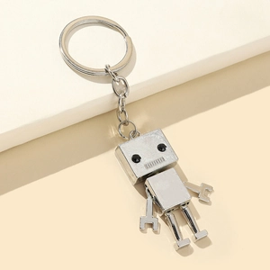 Silver alloy robot keychain with movable limbs and wrench hands on a modern pedestal