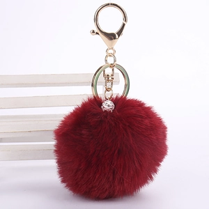 Macro detail of burgundy faux rabbit fur keychain with sparkling rhinestone ball and gold clasp