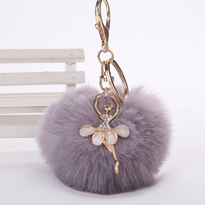 Détail d'un porte-clés pompon en fausse fourrure avec une danseuse de ballet dorée