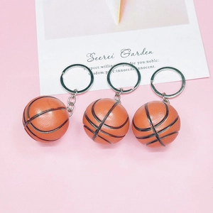 Three realistic orange basketball keychains with black grain on pink background