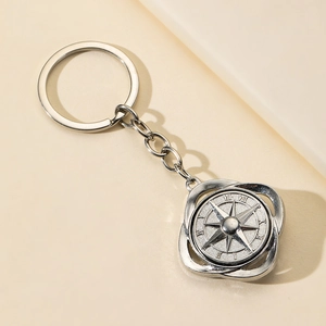 Rotating alloy compass keychain with roman numerals and star design on beige background