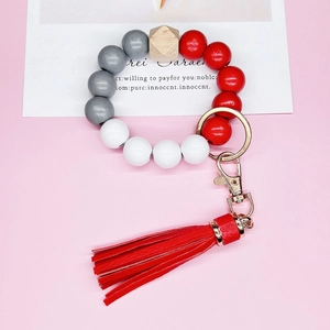 Detail of beaded keychain bracelet with red leather tassel and hexagonal wood bead