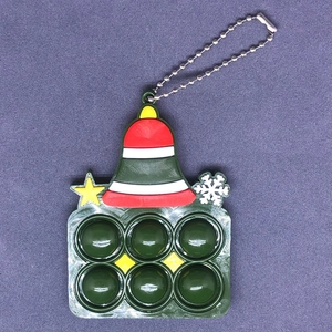 Dettaglio di un portachiavi pop-it a forma di campana di Natale verde con motivi a stella